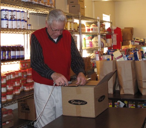 A volunteer with Action Ministries Rome prepares a box of food for distribution. (website photo)